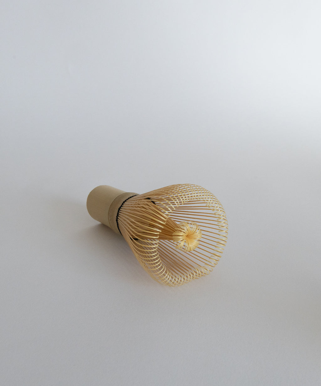 Premium bamboo chasen whisk at a slight angle. Essential matcha accessory.