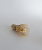 Premium bamboo chasen whisk at a slight angle. Essential matcha accessory.