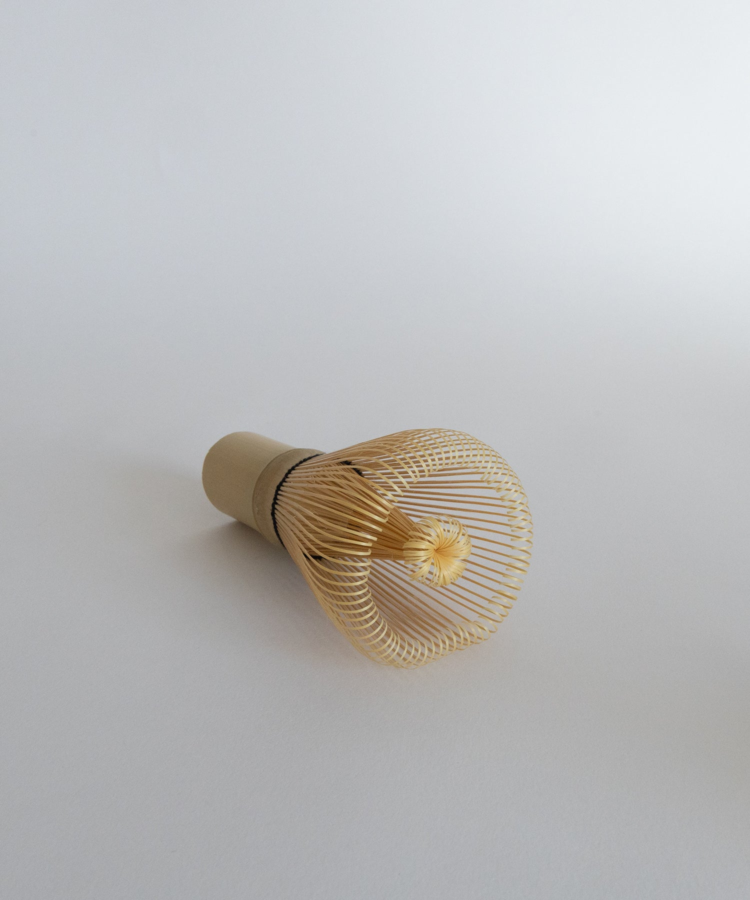 Premium bamboo chasen whisk at a slight angle. Essential matcha accessory.